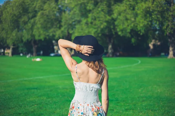 Young woman with hat standing in park — Stock Photo, Image