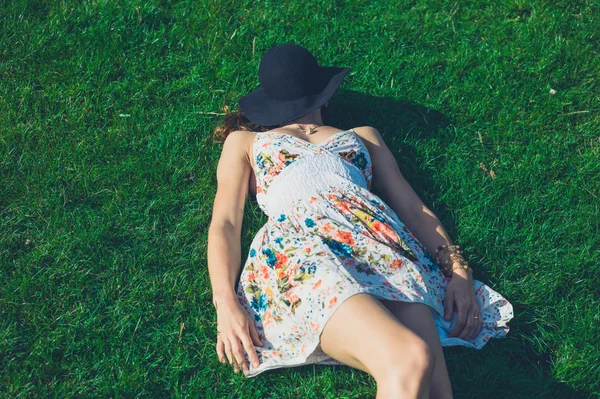 Genç kadın çimlerin üzerinde yatıyor. — Stok fotoğraf