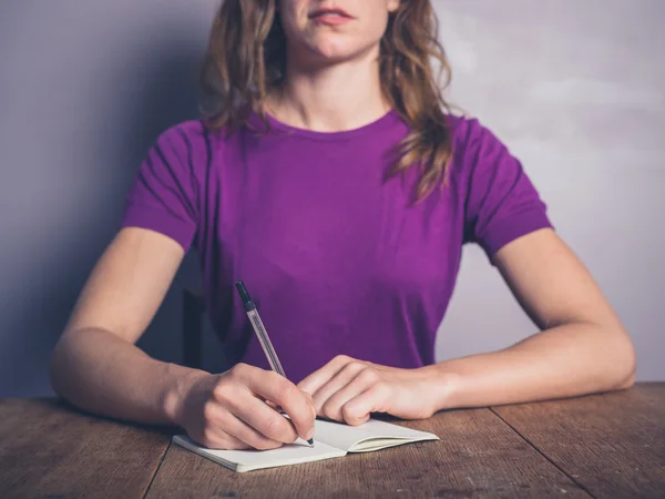 Doordachte jonge vrouw schrijven in Kladblok — Stockfoto