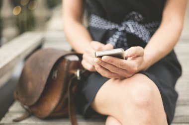 Telefon ile şehirde bankta genç kadın