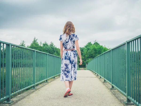 Woman walking on footbridge in country — Stock Photo, Image