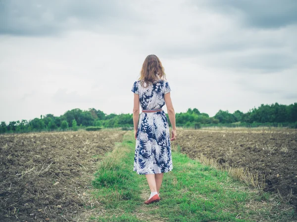 Mujer joven caminando en el campo estéril — Foto de Stock
