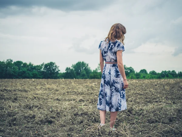 Mujer joven de pie en el campo estéril en el día nublado — Foto de Stock