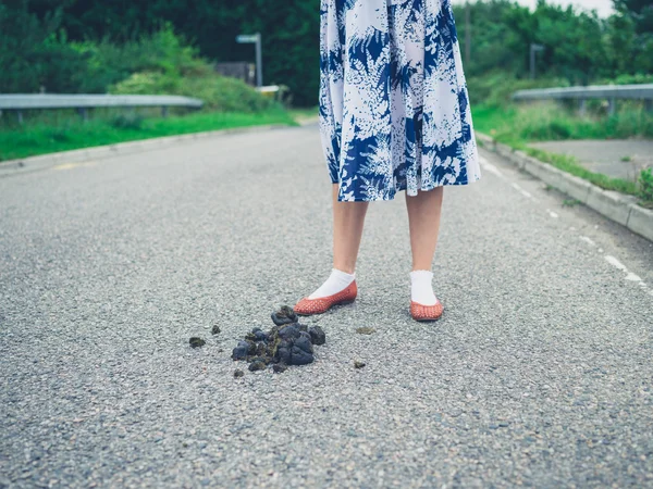 Woman standing in road by horse dung — Stock Photo, Image