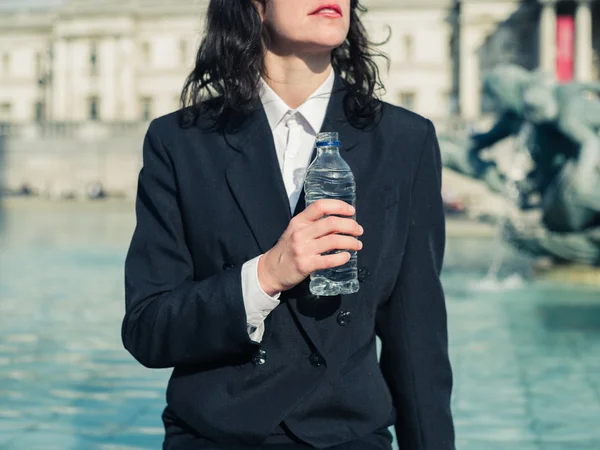 Junge Geschäftsfrau trinkt Wasser am Brunnen in der Stadt — Stockfoto