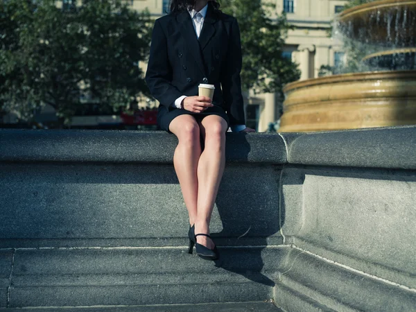 Young businesswoman with coffee by fountain — Stockfoto