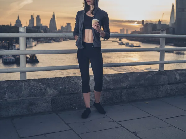 Athletic young woman with cup in London at sunrise — Stockfoto