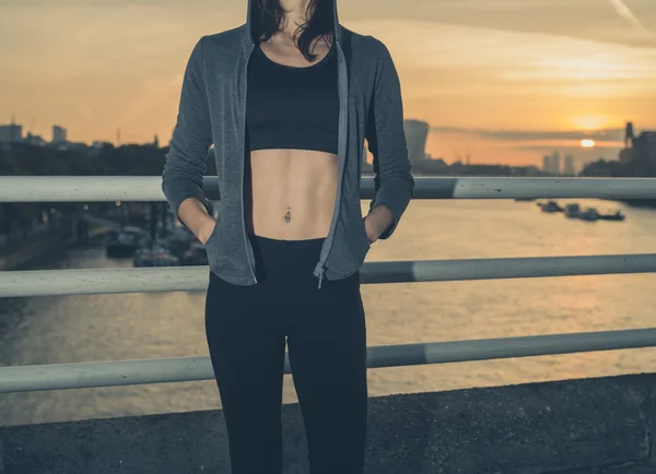 Athletic young woman on bridge at sunrise — Stok fotoğraf