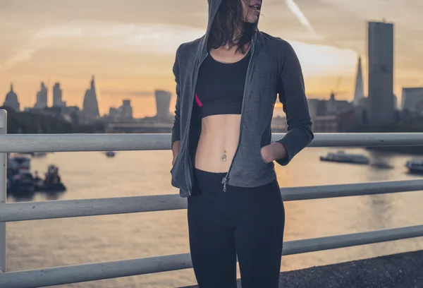 Athletic young woman on bridge at sunrise — Stockfoto
