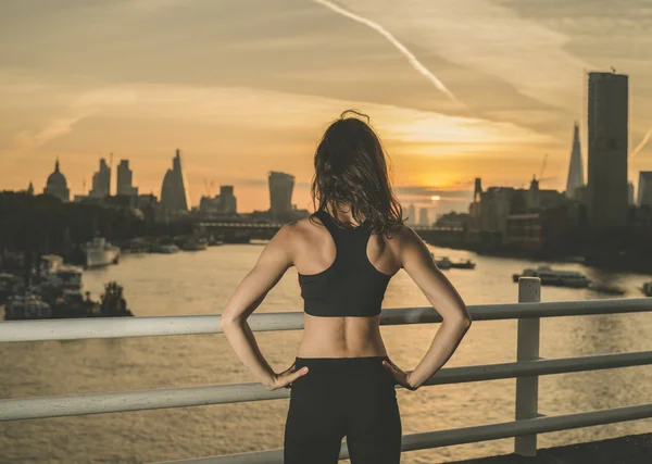 Athletic young woman on bridge at sunrise — Stock fotografie