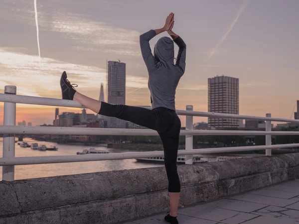 Fitness woman in yoga pose on bridge at sunrise — 图库照片