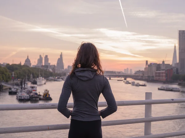 Young woman wearing hoodie on bridge in London at sunrise — Stock Photo, Image