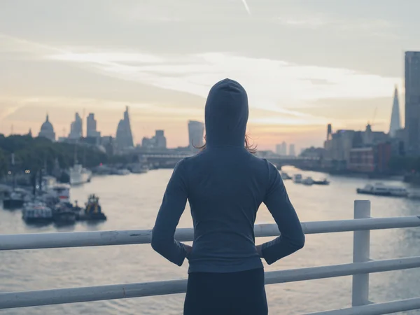 Young woman wearing hoodie on bridge in London at sunrise — Stock Photo, Image