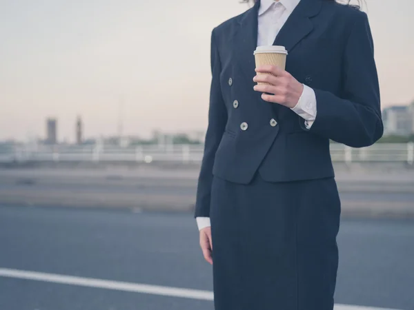 Young businesswoman at sunrise with cup — Zdjęcie stockowe