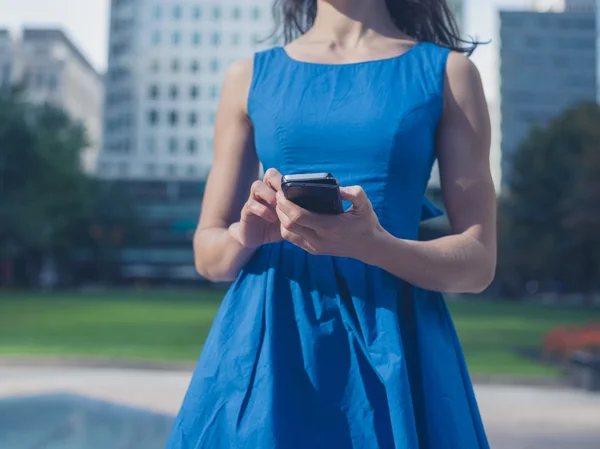 Mujer joven usando el teléfono inteligente en la ciudad — Foto de Stock