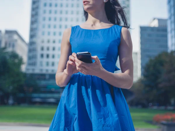 Молодая женщина использует смартфон в городе — стоковое фото
