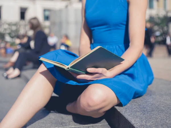 Giovane donna che legge in città — Foto Stock