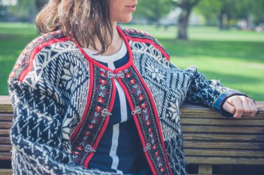 Genç bayan parkta oturuyor.