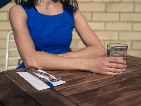 Mladá žena, sedící u stolu před restaurací — Stock fotografie