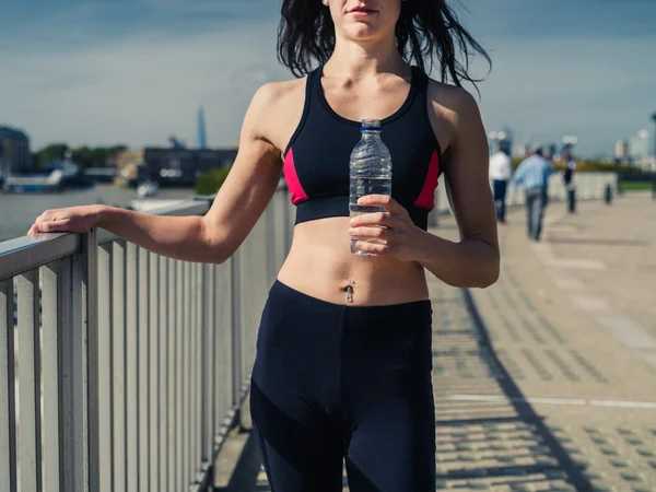 Fit jonge vrouw met water fles in stad — Stockfoto
