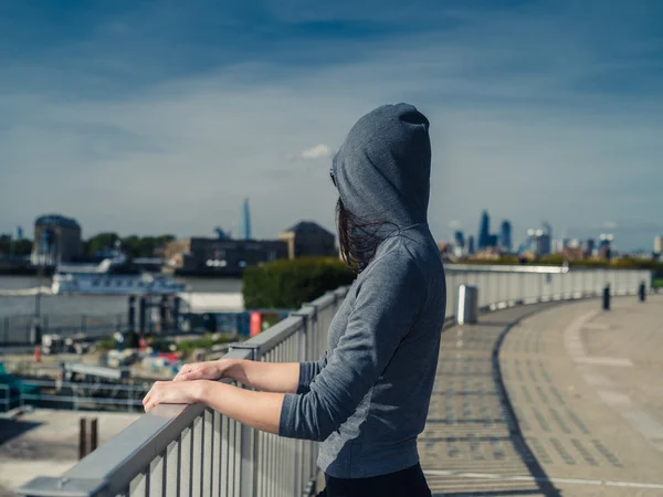 Jonge vrouw in hoodie door fene in stad — Stockfoto