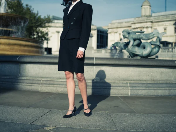 Young businesswoman standing by a fountain in the city — Stock Photo, Image