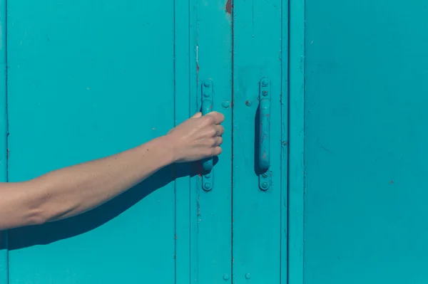 Jovem mão feminina agarrando porta azul — Fotografia de Stock