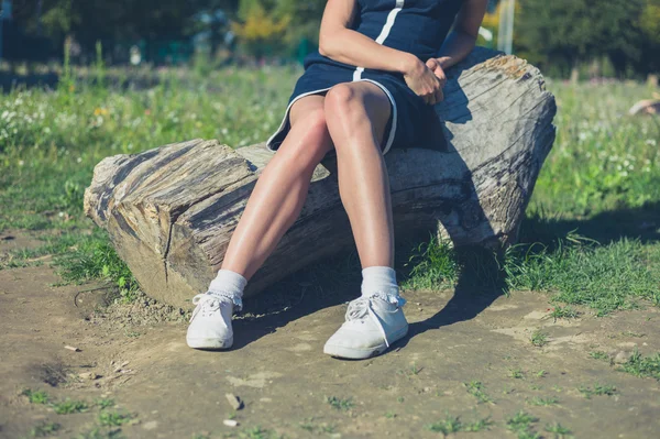 Young woman relaxing on log in park — Stock Photo, Image