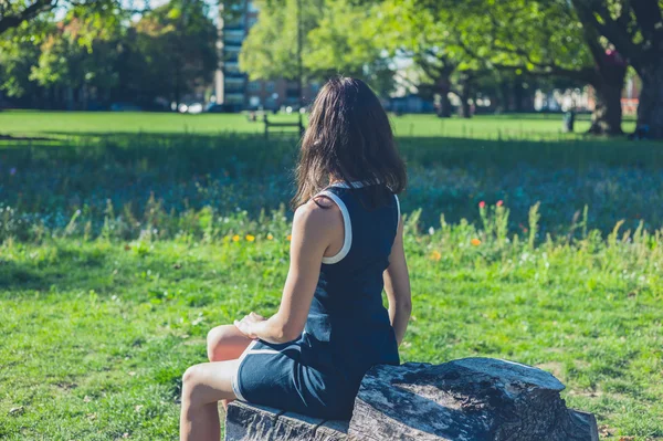 Молодая женщина отдыхает на бревно в парке — стоковое фото