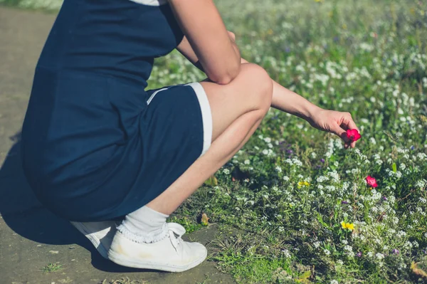 Jonge vrouw bloemen plukken in een park — Stockfoto