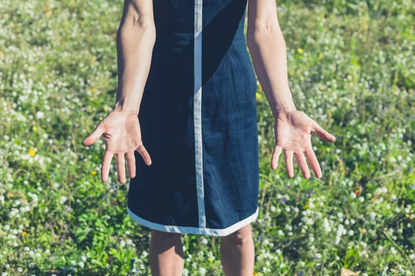 Frau zeigt ihre Hände auf einer Wiese — Stockfoto