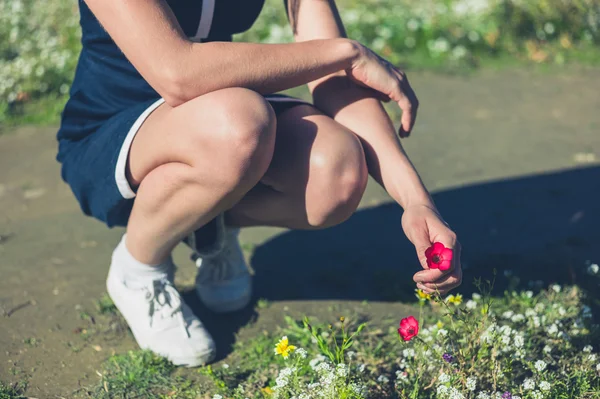 Jovem mulher colhendo flores em um parque — Fotografia de Stock