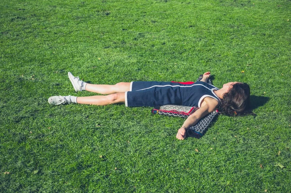 Jovem mulher relaxando na grama em um parque — Fotografia de Stock