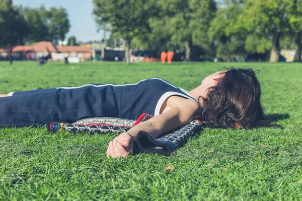 Jonge vrouw ontspannen op het gras in een park — Stockfoto