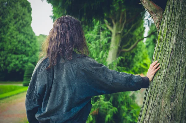 Jonge vrouw leunend tegen boom — Stockfoto