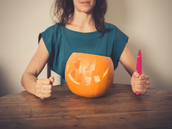 Junge Frau schnitzt eine Kürbislaterne — Stockfoto