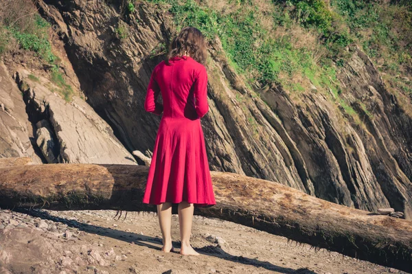 Kvinna i röd står på stranden — Stockfoto