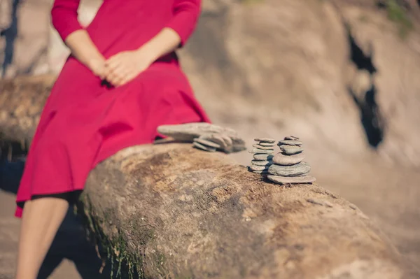 Vrouw zittend op strand met kleine stenen — Stockfoto