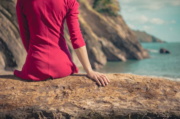 Mladá žena v červených šatech relaxaci na pláži — Stock fotografie