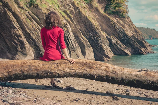 Ung kvinna i röd klänning avkopplande på stranden — Stockfoto