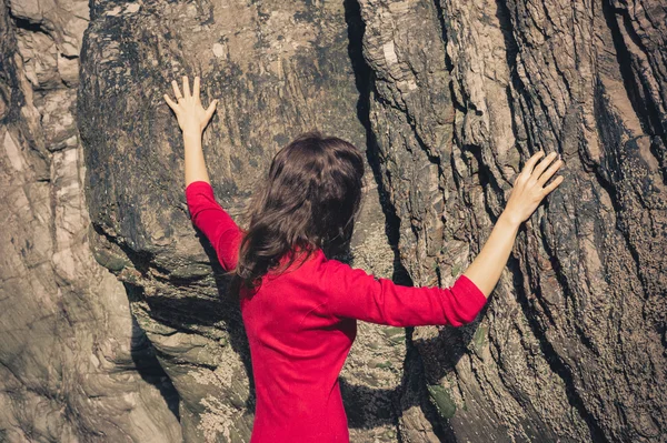 Mulher de vestido vermelho tocando parede de rocha — Fotografia de Stock