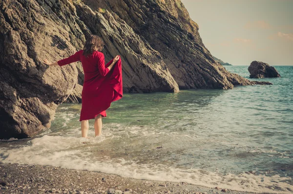 Giovane donna che cammina nel surf sulla spiaggia — Foto Stock