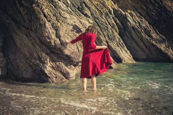 Jovem mulher caminhando no surf na praia — Fotografia de Stock