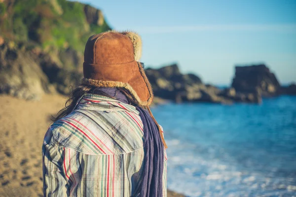 Junge Frau mit Pelzmütze am Strand — Stockfoto