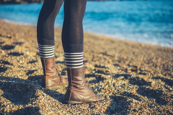 Legs of young woman standing on beach — Stock Photo, Image