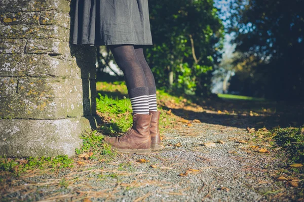 Ноги молодой женщины в сельской местности за стеной — стоковое фото