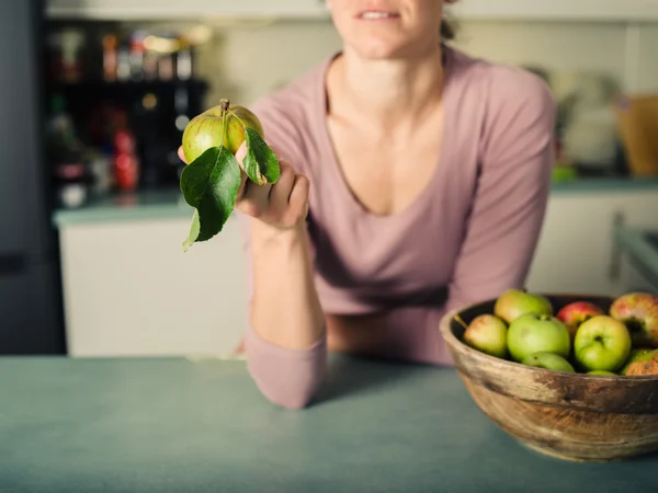 Young woman with apple in kitchen — Stock Photo, Image