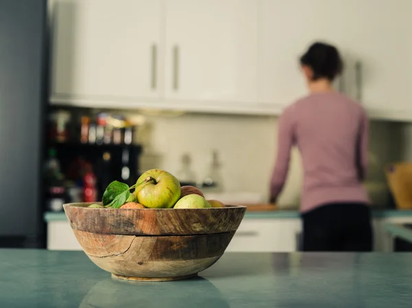 Tigela de maçãs na cozinha com mulher no fundo — Fotografia de Stock