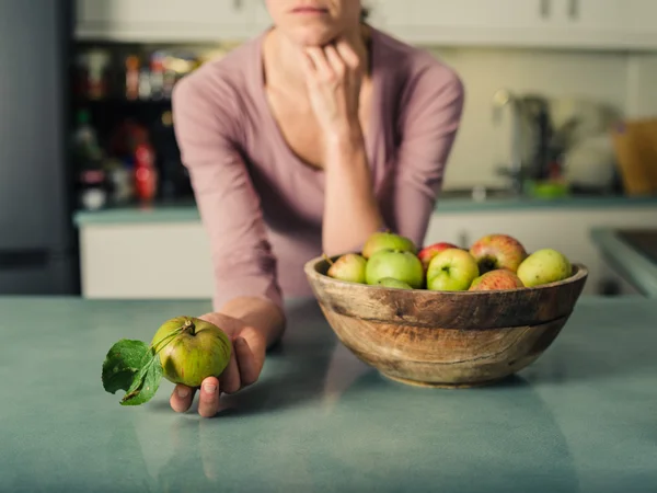 Νεαρή γυναίκα με μήλα στην κουζίνα — Φωτογραφία Αρχείου