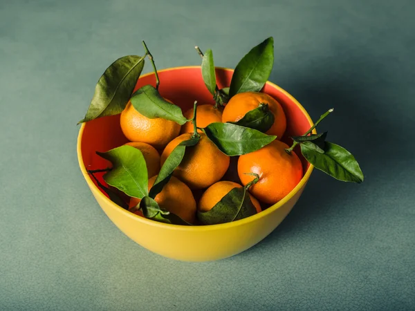 Bowl of oranges on green table — Stock Photo, Image